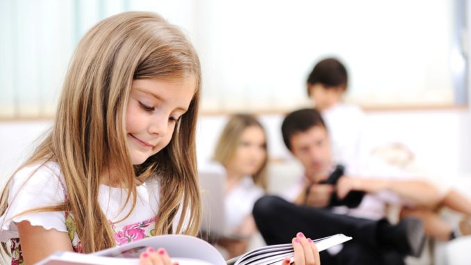 Little girl reading in home, indoor with happy family